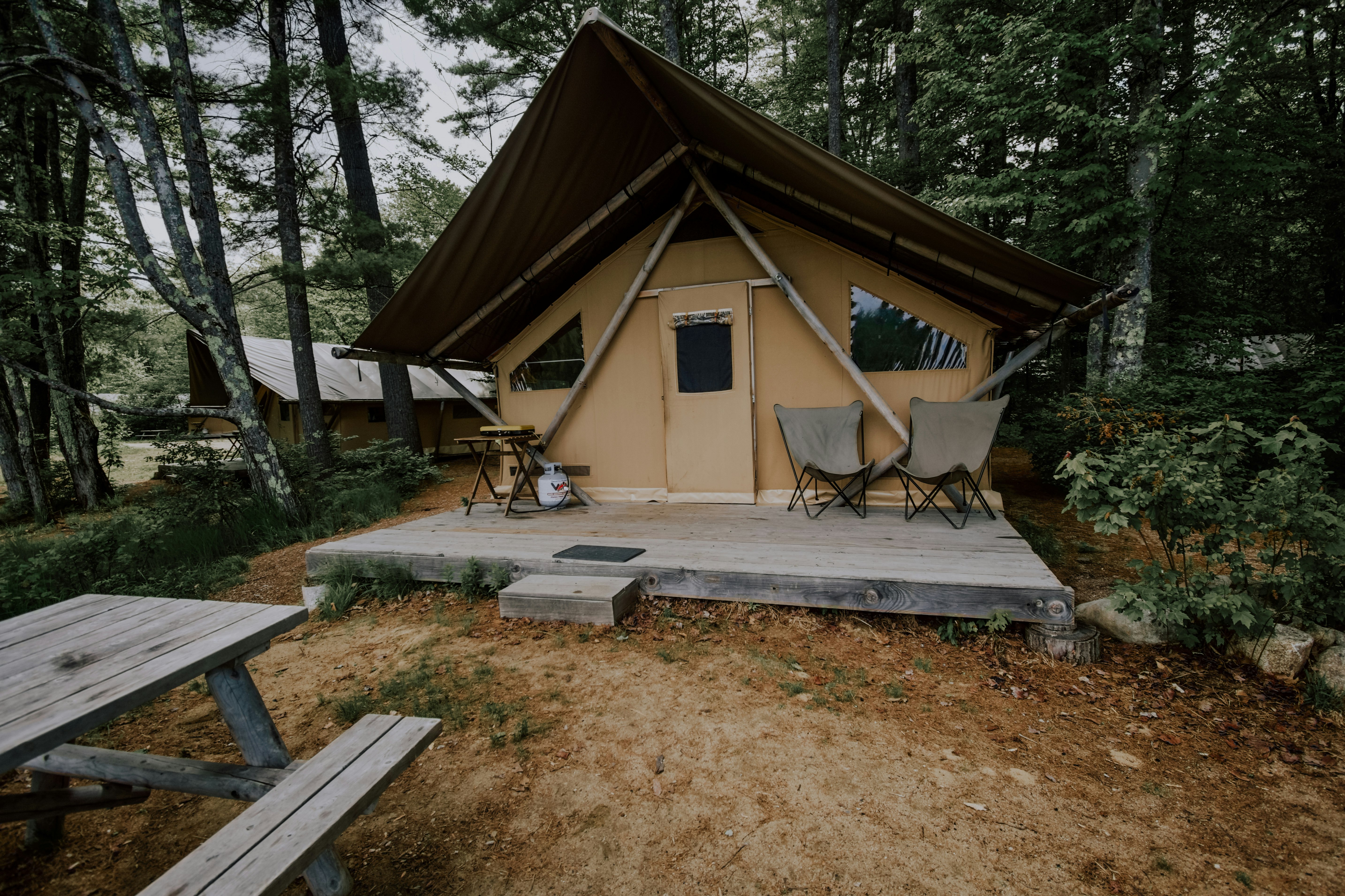 brown and white tent under green trees during daytime